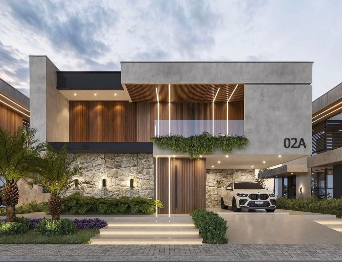 Fachada de una villa moderna al anochecer, con las lamas de madera retroiluminadas sobre el muro de piedra.